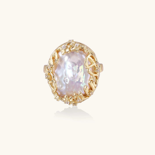 Ornate gold-plated ring with large baroque pearl in decorative vine-like setting with small crystal accents