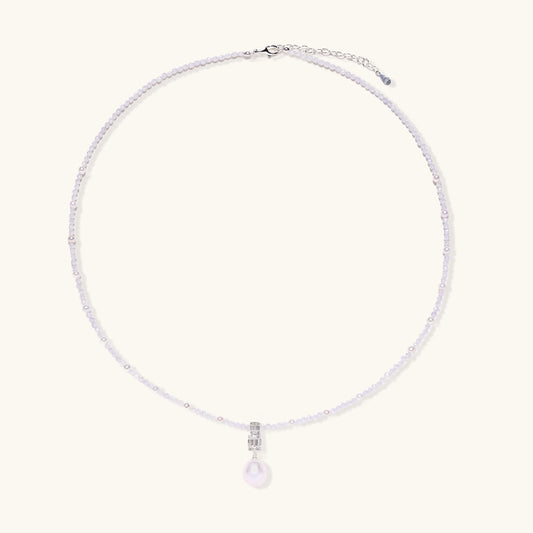 Delicate beaded necklace with lavender crystals, white pearls, and crystal pendant with pearl drop on white background.
