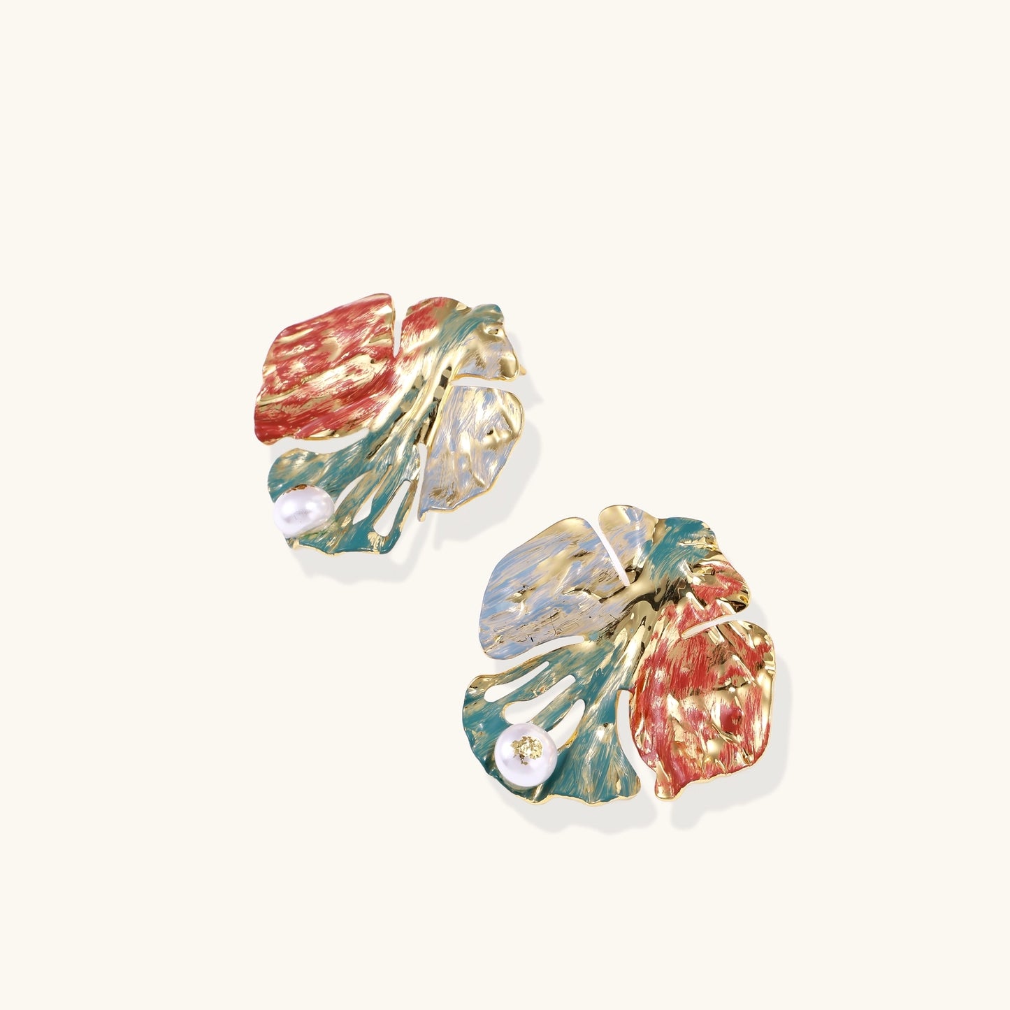 Colorful enamel monstera leaf earrings with pearl accents in teal, coral and gold tones on neutral background.