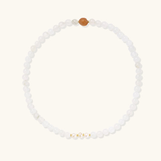 Stretch bracelet with white jade beads, freshwater pearls, and orange agate centerpiece on cream background.