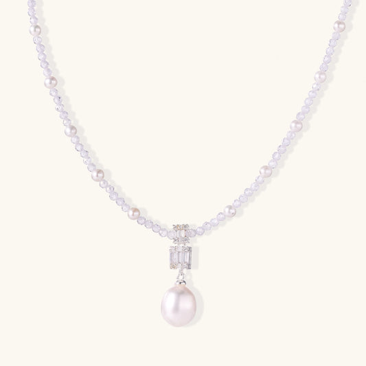 Delicate beaded necklace with lavender crystals, white pearls, and crystal pendant with pearl drop on white background.
