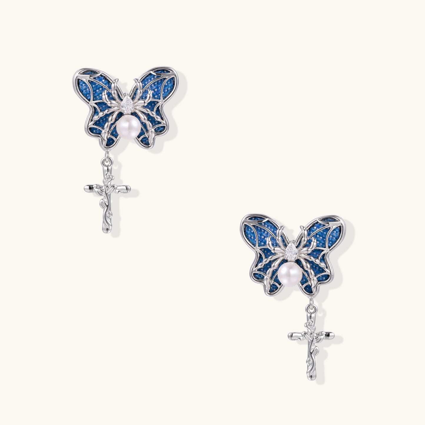 Ornate gold-plated butterfly earrings with blue enamel wings, white pearl centers, and silver cross dangles