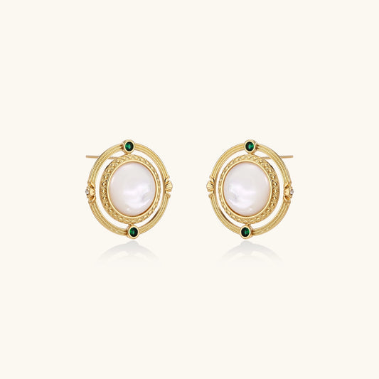 Close-up of gold-plated circular earrings with white mother-of-pearl centers and green zirconia accents on cream background.