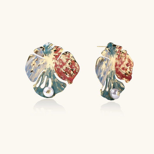 Colorful enamel monstera leaf earrings with pearl accents in teal, coral and gold tones on neutral background.
