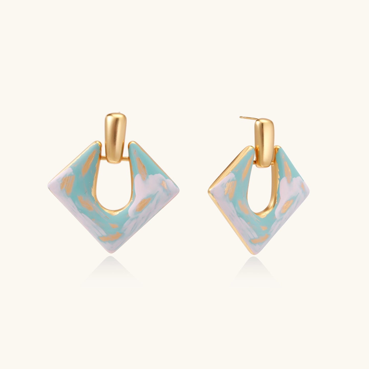 Diamond-shaped gold-plated earrings with pastel marble enamel in turquoise and lavender swirls on beige background