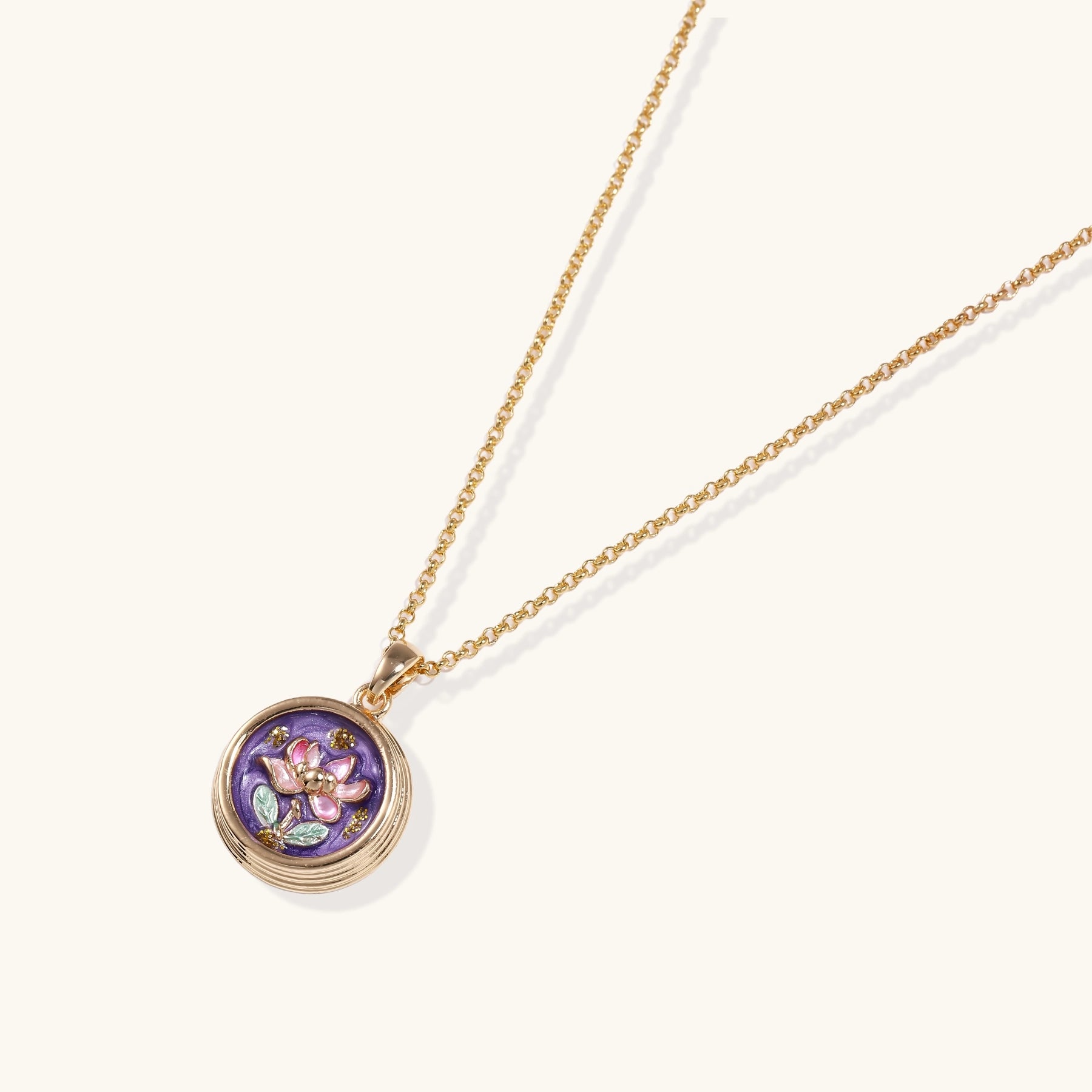 Gold-plated necklace with purple enamel pendant featuring pink floral design on white background