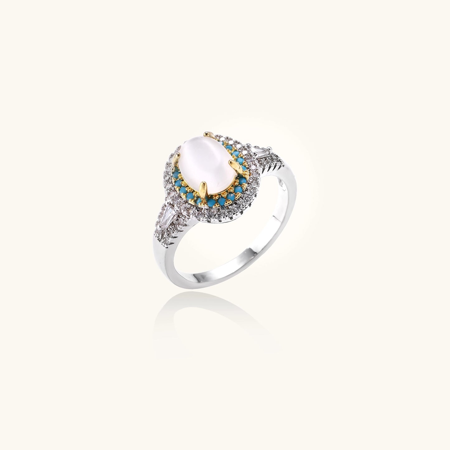 Gold-plated ring with oval cat's eye stone center, blue accent stones, and crystal halo on white background.