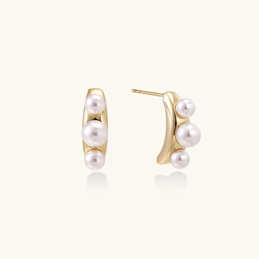 Delicate gold stud earrings with three lustrous white freshwater pearls arranged in an organic curved line.