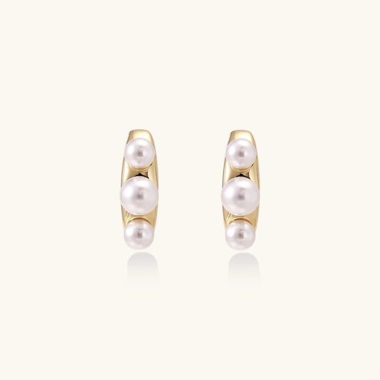 Delicate gold stud earrings with three lustrous white freshwater pearls arranged in an organic curved line.