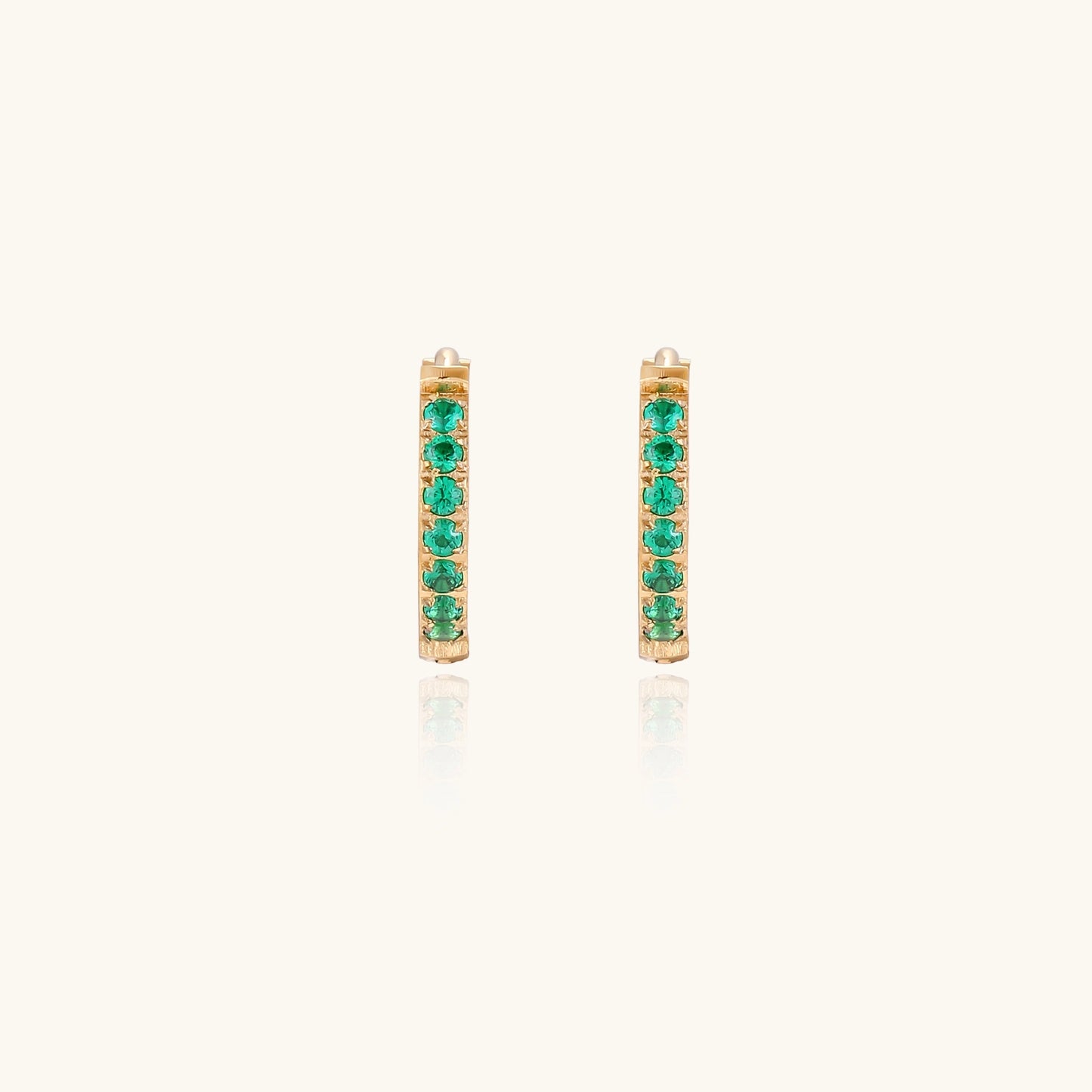 Small gold-plated huggie hoop earrings with emerald green cubic zirconia stones, one open showing hinge mechanism